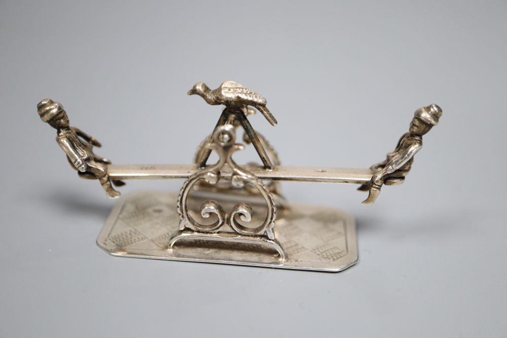 A Dutch white metal toy model seesaw group, 7cm and a white metal mounted thread waxer, 24mm.